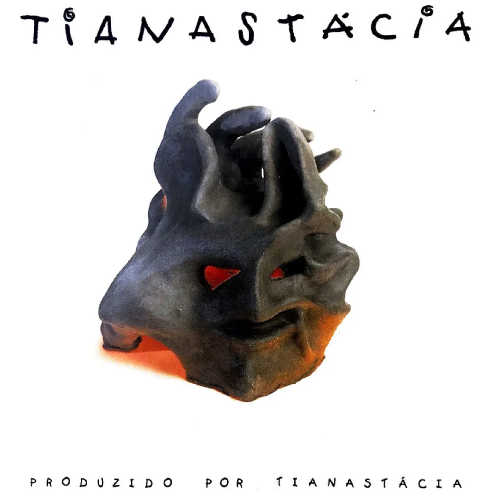 Capa do disco Tianastácia, de 1998, o Álbum Branco: uma escultura de argila escura com olhos vermelhos sobre fundo branco e o nome da banda escrito à mão
