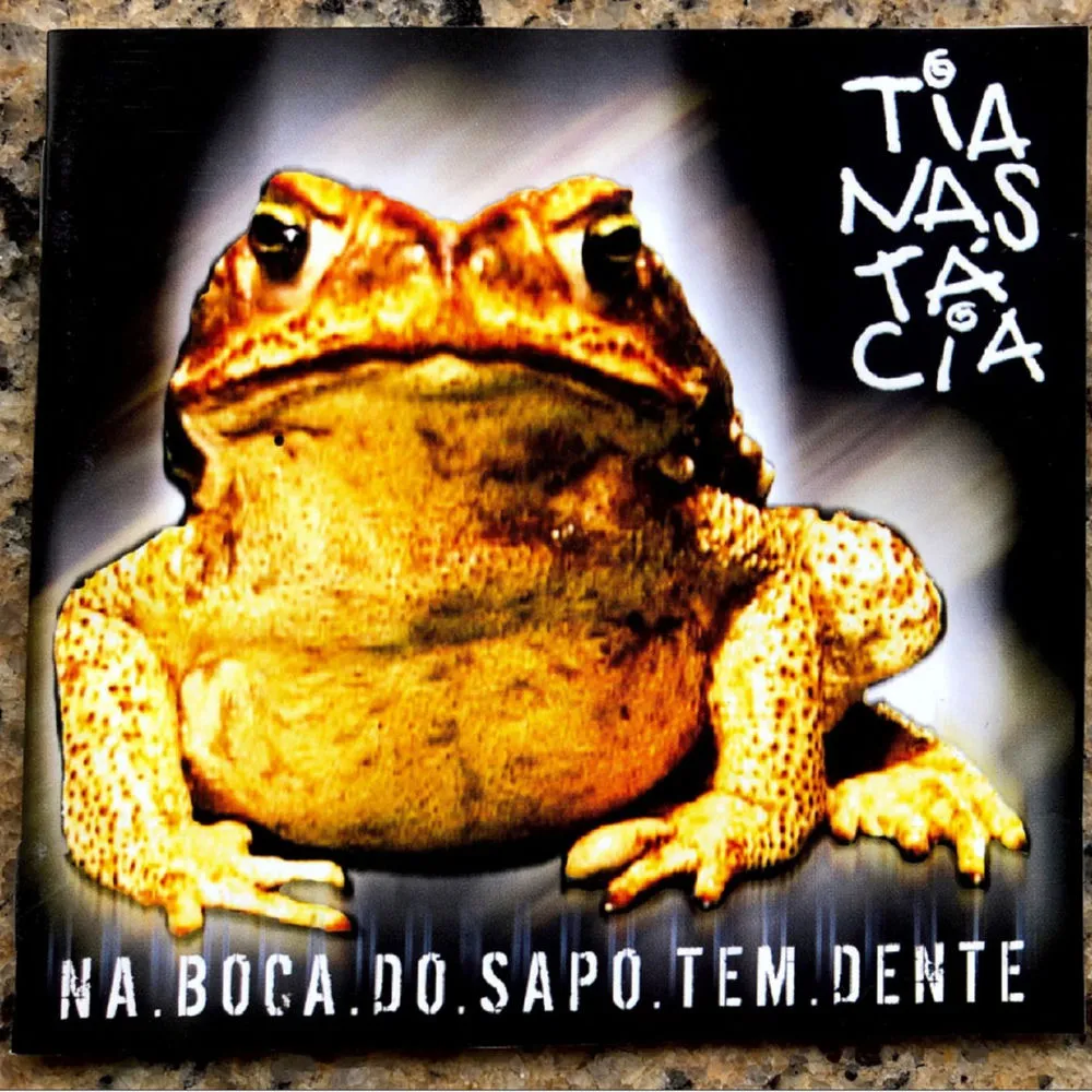 Capa do disco Na Boca do Sapo Tem Dente, de 2004: um sapo grande em close sobre fundo escuro, com o nome Tianastácia no canto